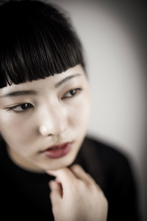 頬杖をついてツンとした表情のオン眉前髪の女性ポートレート