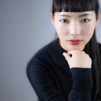 頬杖をついて取り澄ます黒髪の女性のポートレートの写真