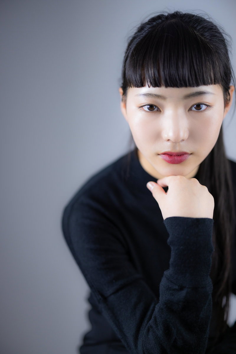 頬杖をつきながら上を見つめる黒髪オン眉の女性ポートレート［モデル：なんこ］