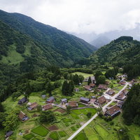 緑の山々に囲まれた相倉集落を一望する空撮の写真