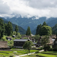 山に雲がかかる相倉合掌造り集落と棚田の風景の写真