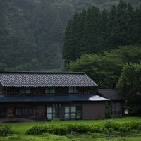 霧雨が降る菅沼集落の合掌造り家屋と山々の景観の写真