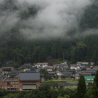 霧覆う南砺市の山と集落、朝焼けに染まる山村風景の写真