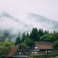 渓谷を覆う霧と相倉合掌造り集落の朝景色、茅葺き屋根の伝統建築の写真