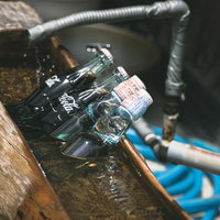 氷の上に置かれた冷えたコーラとラムネの瓶の写真