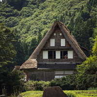 相倉合掌造り集落の合掌造りの家から外を覗く人形の写真