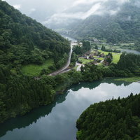 霧が立ち込む庄川峡と菅沼の合掌造り集落を空撮で捉えた風景の写真