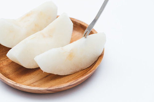 木製の皿に並べたカットした梨とスプーン、秋の味覚