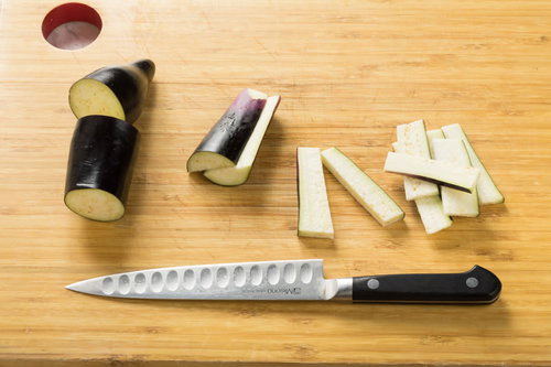 木製のまな板で輪切りにカットした長なすの調理風景