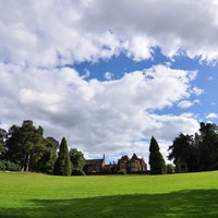 緑の芝生と庭園に囲まれたハンプシャー州のマナーハウスの外観の写真
