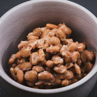 茶色いお椀に盛られた粒納豆、豆粒の質感とつやの写真