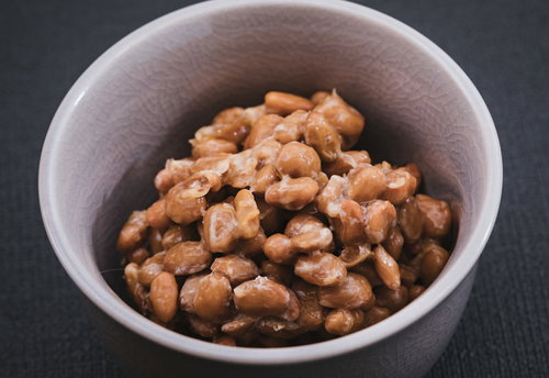 茶色いお椀に盛られた粒納豆、豆粒の質感とつや