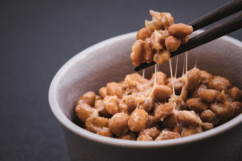 白い器の丸大豆納豆を箸で持ち上げた糸引き