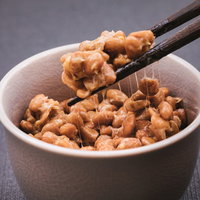 箸でつまんだ納豆の粘り、糸を引く大豆発酵食品の写真