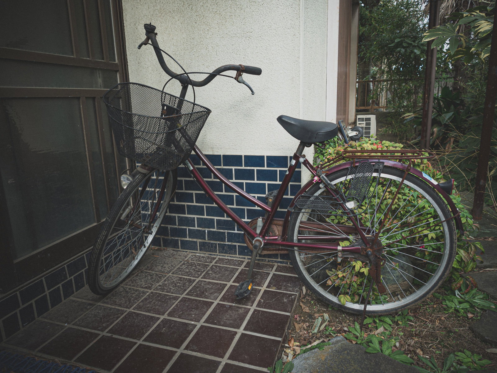 空き家の玄関先に置かれた錆びた古い自転車