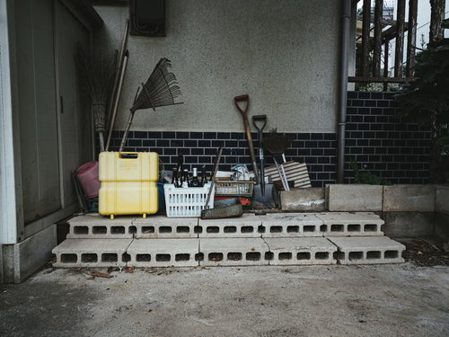 廃屋の古いブロック塀とスコップが置かれた倉庫