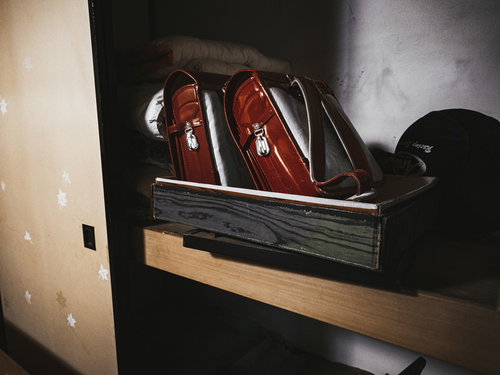 赤いランドセルが並ぶ薄暗い押し入れ。昭和レトロな廃屋の不気味な空間
