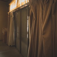 昭和レトロな廃屋に垂れ下がる閉め切ったカーテンと雨戸の写真