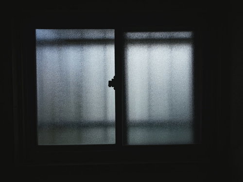 曇りガラスの窓から光が差し込む日当たらない部屋