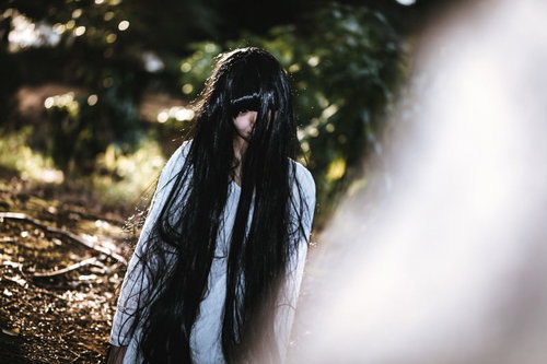 呆然と立ちすくむ不気味な長い黒髪の女性