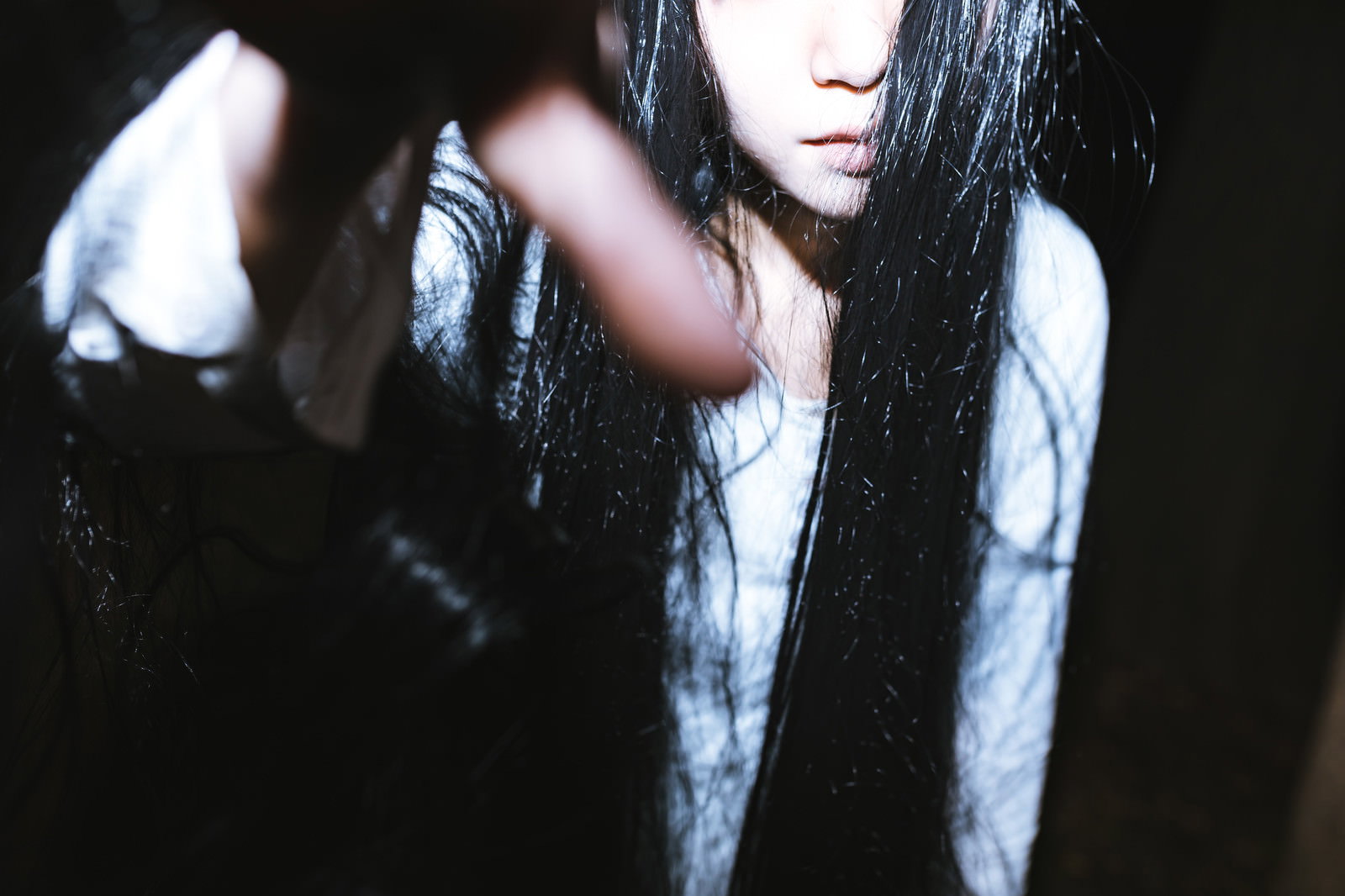 暗闇の中で長い黒髪をなびかせる女性の姿［モデル：緋真煉］