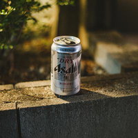 ブロック塀の上に置き去りにされたビールの缶の写真