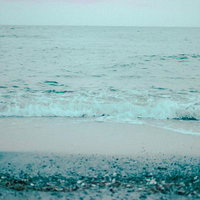 小石の浜に寄せる穏やかな波打ち際の海風景の写真