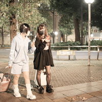 深夜の街で待ち合わせするキャリーケース姿の女性たちの写真