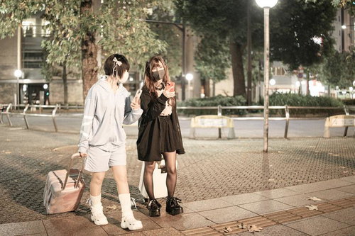 深夜の街で待ち合わせするキャリーケース姿の女性たち