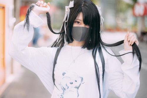 原宿系のマスク女子が黒髪を両手でつかむポーズ