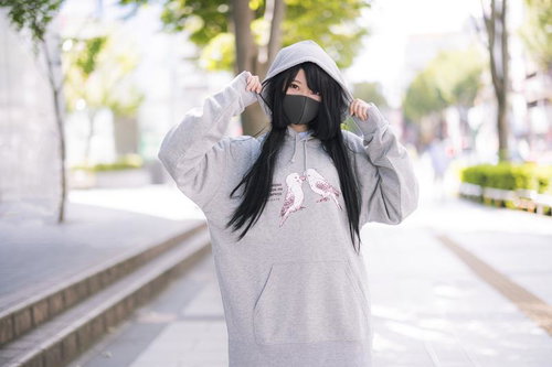 インコパーカーのフードをかぶるマスク女子