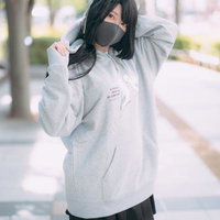 グレーの大きめパーカーでマスク姿の若い女性のストリートファッションの写真