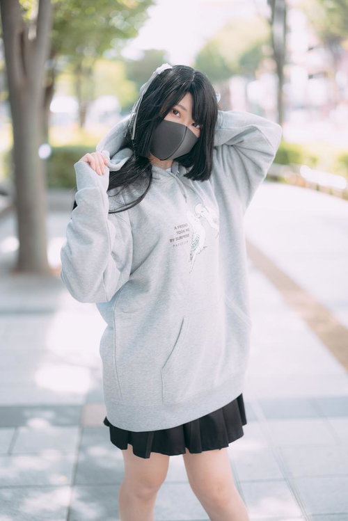 グレーの大きめパーカーでマスク姿の若い女性のストリートファッション