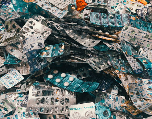 床に散乱した大量の錠剤とカプセル、空ケース