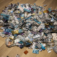 木目の床に散らばった大量の錠剤とカプセルの写真