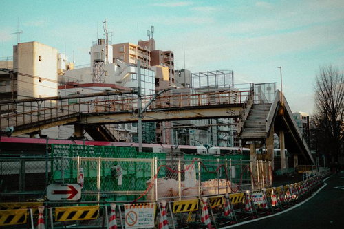 緑のフェンスに囲まれた再開発工事現場と古い高架歩道橋（渋谷）