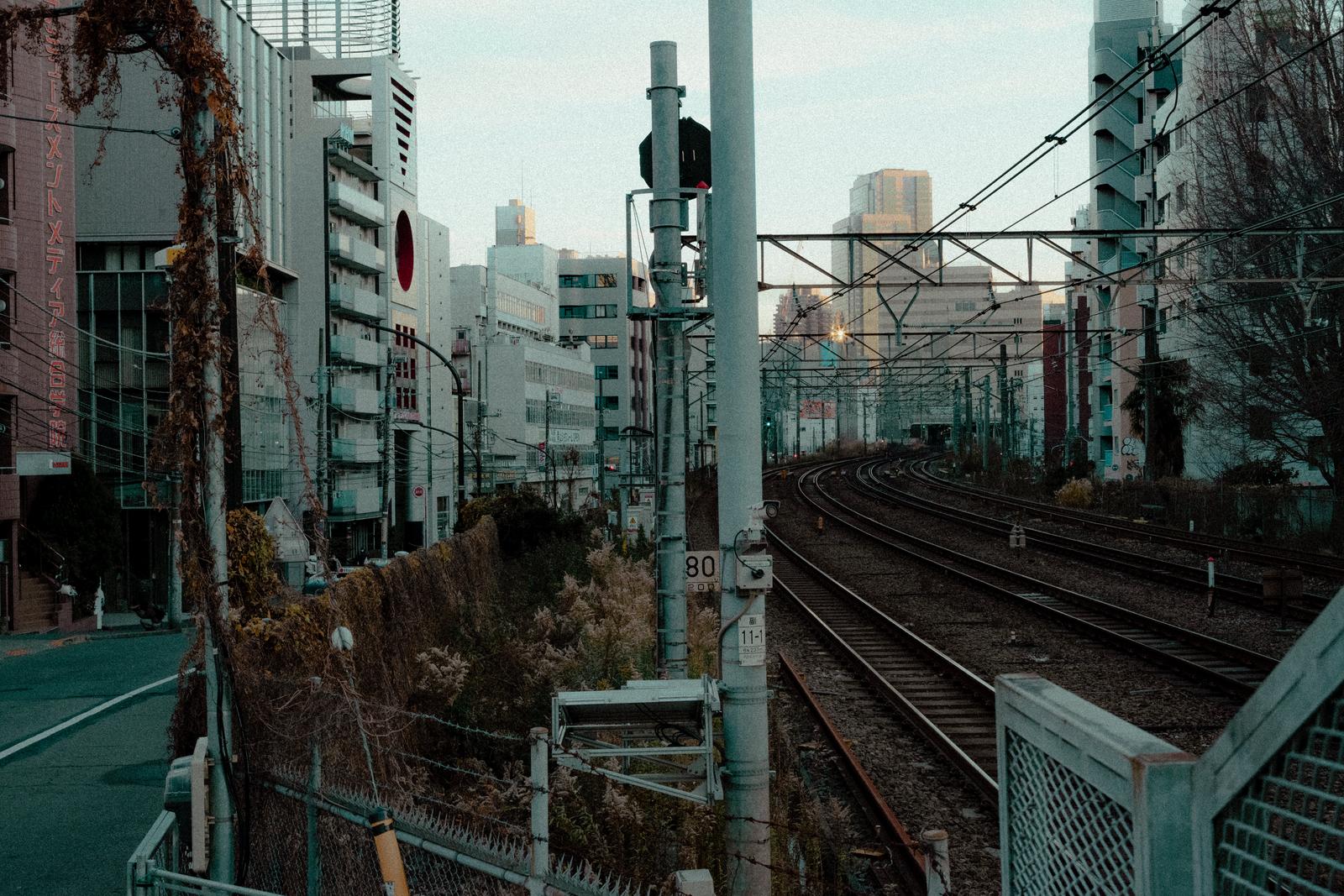 高層ビルに囲まれた複数の鉄道線路が走る都市風景