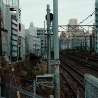 都会の高層ビルに囲まれた鉄路が交差する街並みの写真