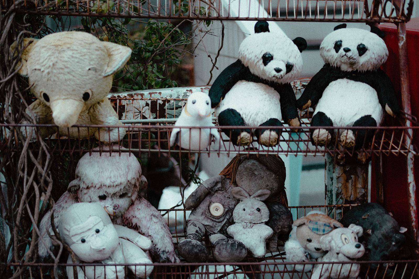 古い籠に詰め込まれたパンダのぬいぐるみと色褪せたテディベアや人形