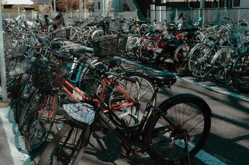 アスファルト駐輪場に並ぶ赤と黒の自転車群