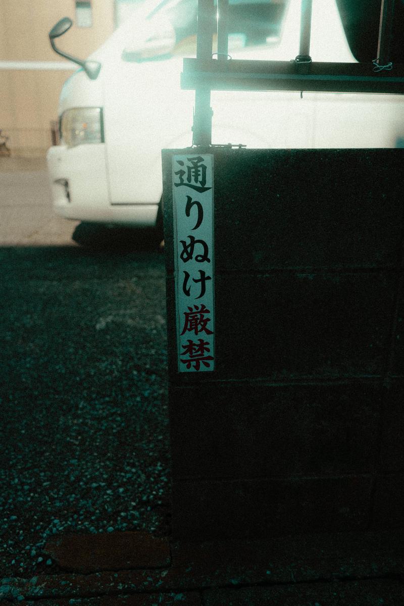 路地入口に下げられた黒地に白文字の通り抜け厳禁の注意札
