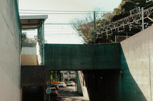 コンクリートの壁が囲む高架下の車道と都市の日常