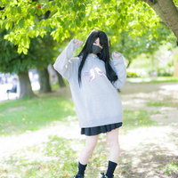 インコパーカーを着た黒髪マスク女子が公園で佇むの写真