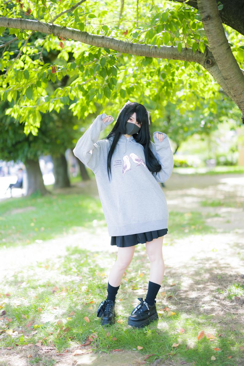 公園の樹木の下でグレーのインコパーカーを着たマスク女子［モデル：緋真煉］