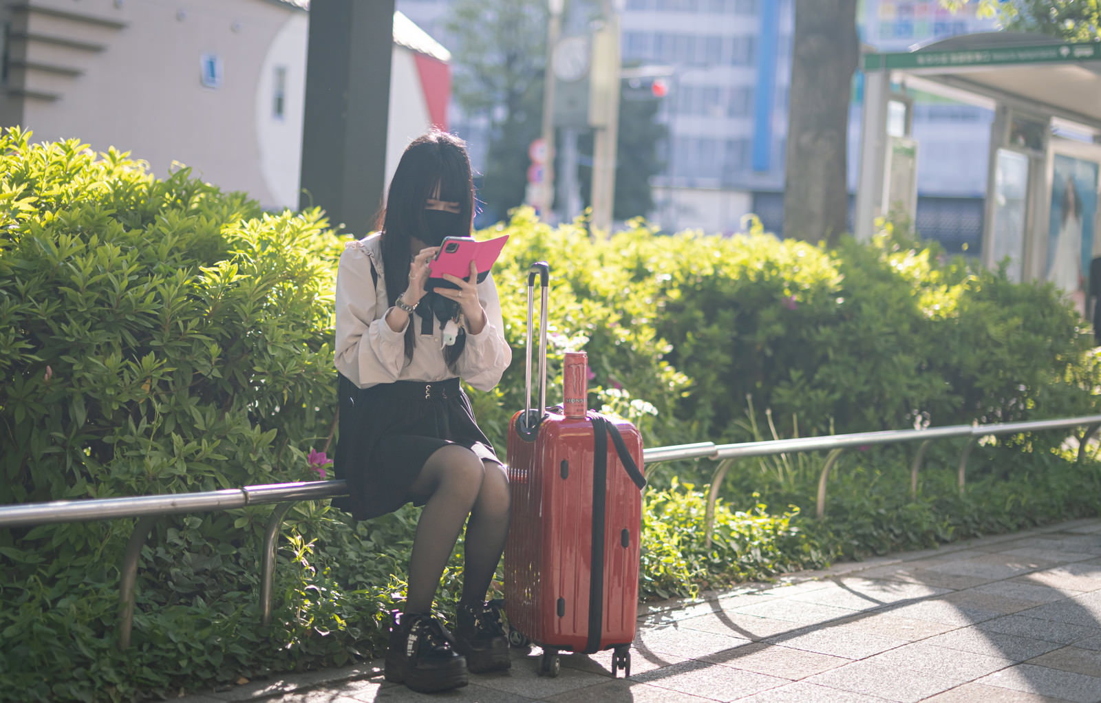 マスクを着けた地雷系女子がキャリーケースを持って立っている［モデル：緋真煉］