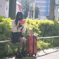 道に迷ったマスク姿の地雷系女子とキャリーケースの写真