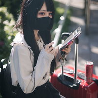 推しと旅行中のマスク女子、キャリーケース横でスマホを見つめるの写真