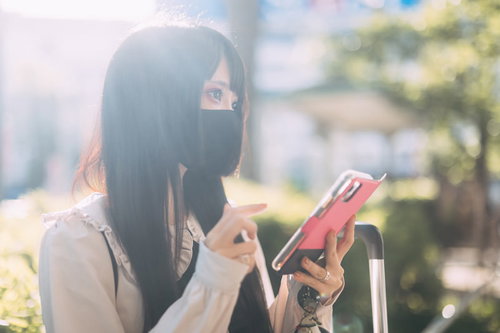 スマートフォンを持つマスクする地雷系女子