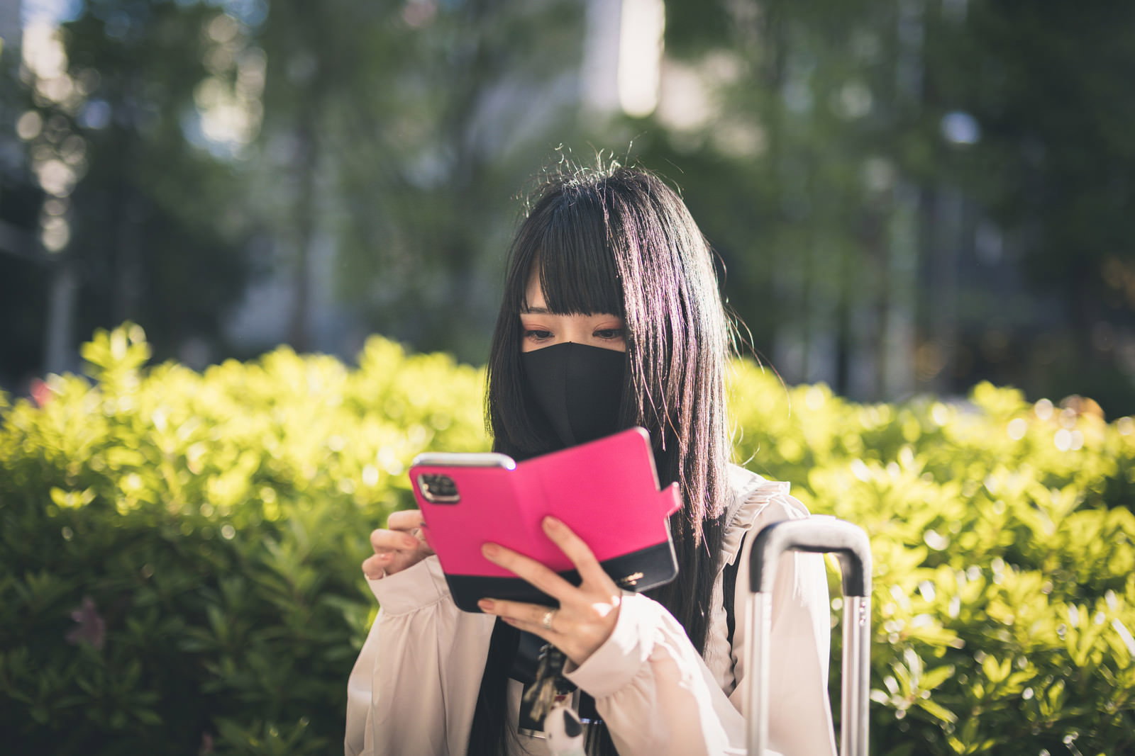 マスクをつけてスマートフォンを見つめる女性［モデル：緋真煉］