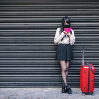 赤いキャリーケースと地雷系女子のトラベルコーディネートの写真